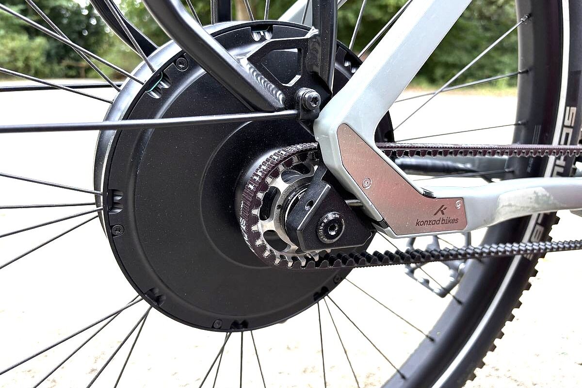 Motor Großaufnahme eines schwarzen Hinterradmotors, davor der Antriebsrimen, an einem grauen Fahrrad.